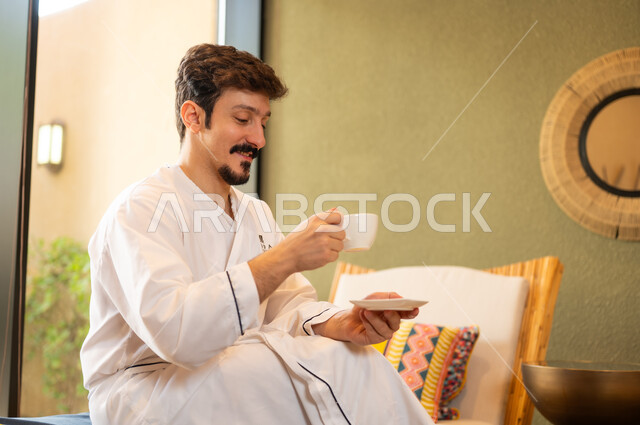 رجل سعودي برداء الحمام الأبيض يشرب القهوة في السبا