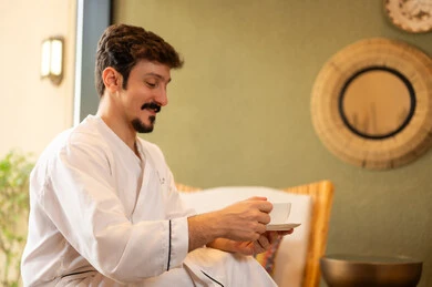 Man in White Bathrobe Drinking Coffee in Spa Lounge