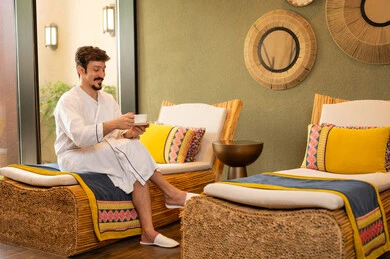 رجل عربي يرتدي رداء حمام أبيض يسترخي في سبا فاخر