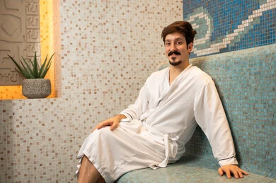 رجل سعودي يرتدي رداء حمام في غرفة البخار