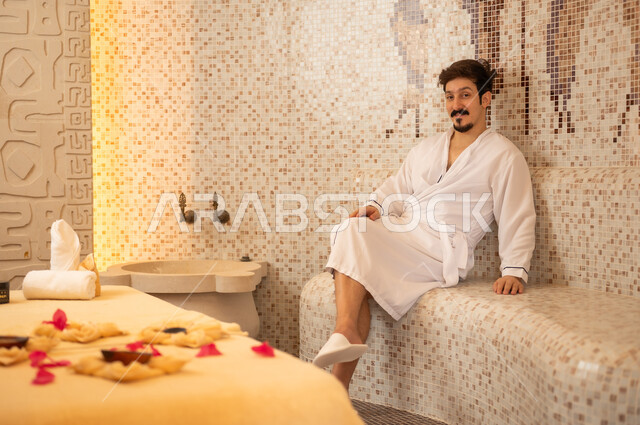 رجل عربي يرتدي رداء حمام يستجم في غرفة بخار
