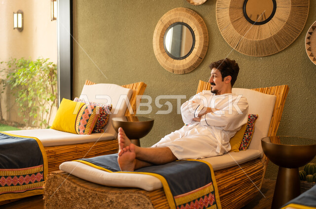 رجل عربي يسترخي في منتجع صحي برداء حمام أبيض