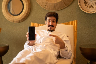 Arab Man in White Thobe Pointing at Smartphone Screen