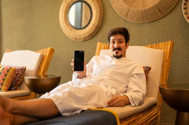 Arab Man in White Bathrobe Holding Smartphone in Spa