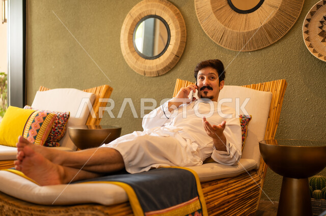Arab Man in Bathrobe Talking on Phone in Spa