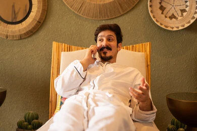 رجل سعودي يتحدث عبر الهاتف الذكي في بيئة تقليدية