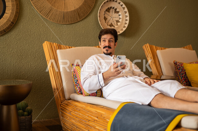 Saudi Man Relaxing in Traditional Spa with Smartphone