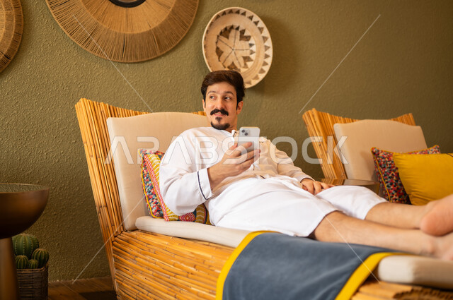 رجل سعودي بالثوب الأبيض يستخدم الجوال في سبا