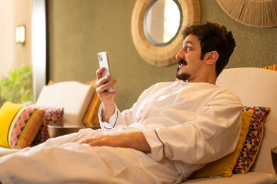 Saudi Man in White Bathrobe Using Smartphone in Spa