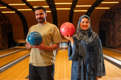 Saudi Couple Holding Bowling Balls in Recreation Center