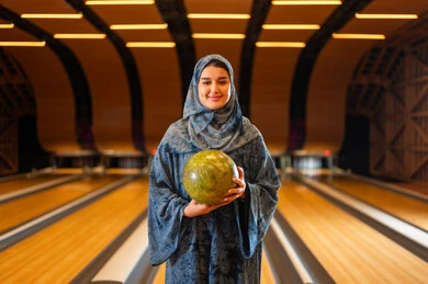 Saudi Woman Holding Bowling Ball in Indoor Alley