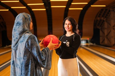 Saudi Women Holding Red Bowling Ball in Alley