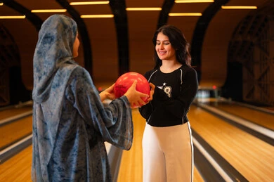 نساء عربيات يلعبن البولينج في مركز ترفيهي