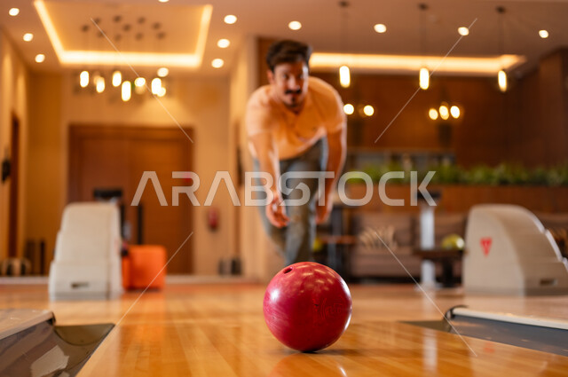 رجل سعودي يلعب البولينج في مركز ترفيهي