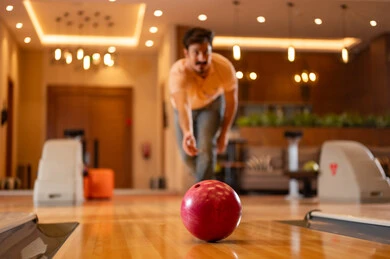 Saudi Man Bowling in Indoor Recreation Center