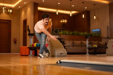 رجل سعودي يلعب البولينج في مركز ترفيهي