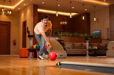 شاب عربي يلعب البولينج في صالة ألعاب حديثة