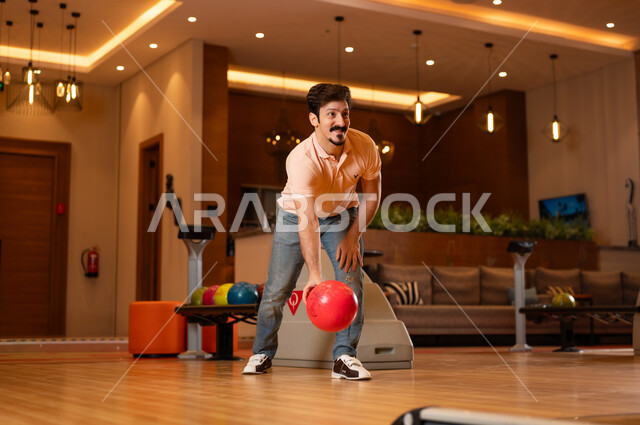 Saudi Man Throwing Red Bowling Ball in Indoor Alley