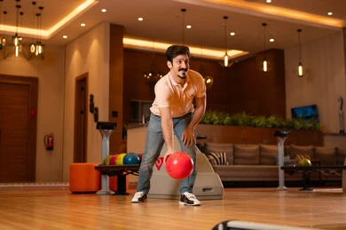 Saudi Man Throwing Red Bowling Ball in Indoor Alley