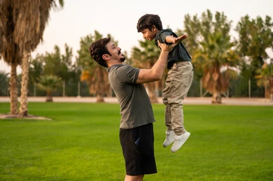 Saudi Father Lifting Son in Public Park Outdoors