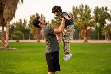 Arab Father Lifting Son in Park at Golden Hour