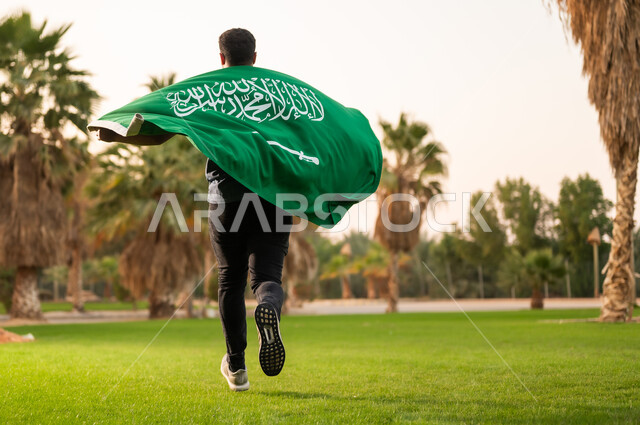 Saudi Man Running with Flag in Park at Sunset