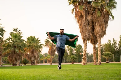 Saudi Man Running with National Flag in Park
