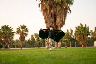 Saudi Boy Running with National Flag in Public Park