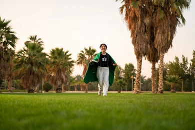 Young Saudi Girl Running with Flag in Park
