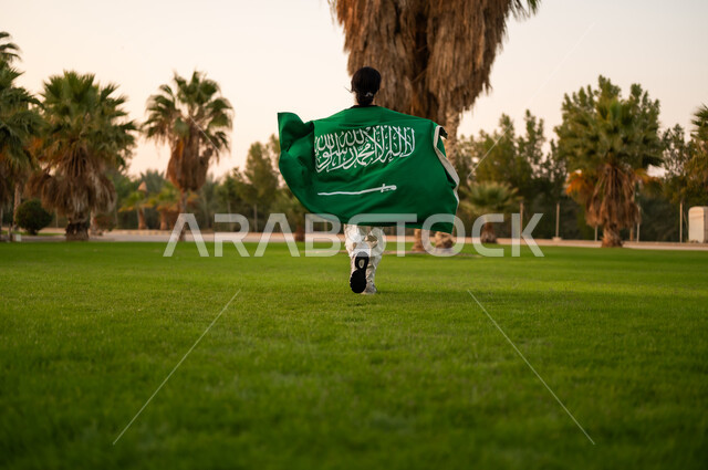 شخص سعودي يركض بالعلم في حديقة وقت الغروب
