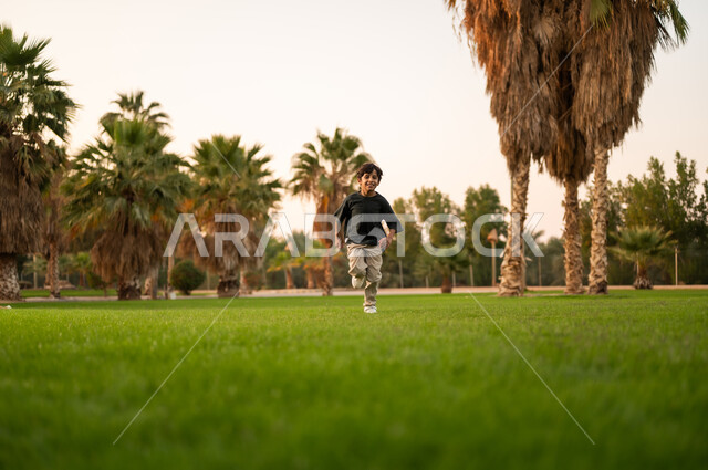 طفل عربي يركض في حديقة خضراء وقت الغروب