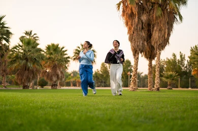 Two Saudi Women Jogging in a Palm Tree Park