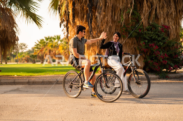 Middle Eastern Couple Cycling in a Public Park High Five