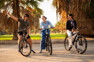 أصدقاء عرب يركبون الدراجات في حديقة عامة وقت الغروب