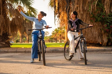 Saudi Women Riding Bicycles in Park at Sunset