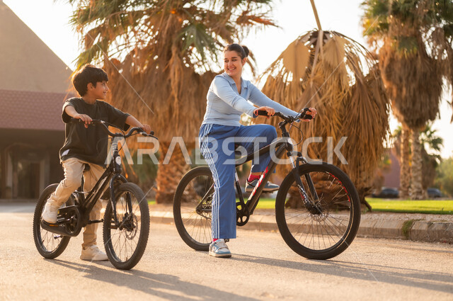 Saudi Mother and Son Riding Bicycles at Sunset