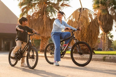 Saudi Mother and Son Riding Bicycles at Sunset