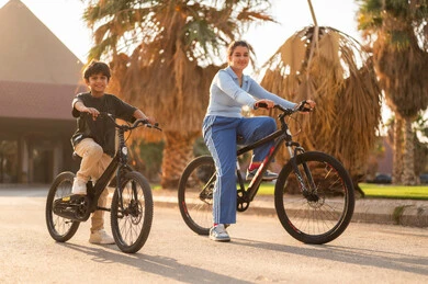 Arab Girl and Boy Cycling Outdoors at Sunset