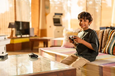 طفل سعودي ممسك بجهاز تحكم ألعاب في غرفة المعيشة