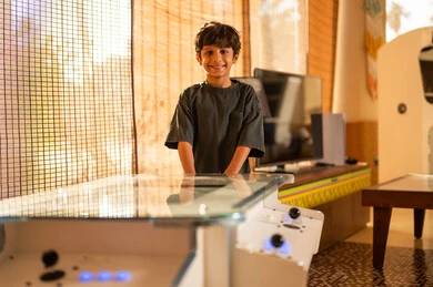Saudi Boy with Arcade Game Table at Home