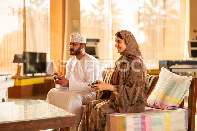 زوجان عمانيان يلعبان ألعاب الفيديو في غرفة المعيشة