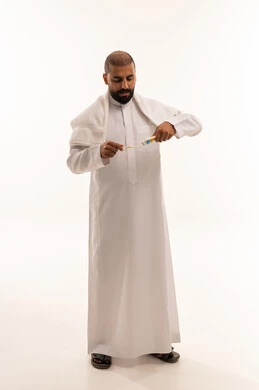 Saudi Man in Traditional Thobe Applying Toothpaste