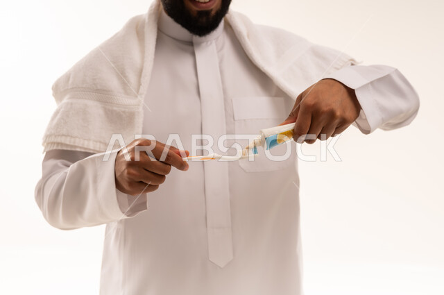 Saudi Man Applying Toothpaste to Brush on White Background
