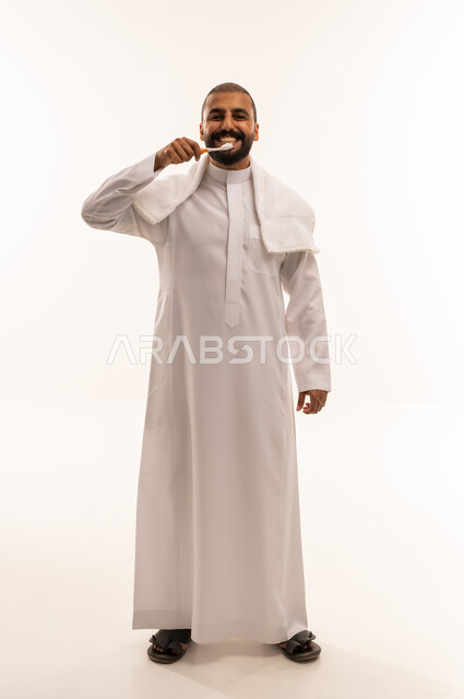 رجل سعودي يرتدي الثوب الأبيض ينظف أسنانه بالفرشاة