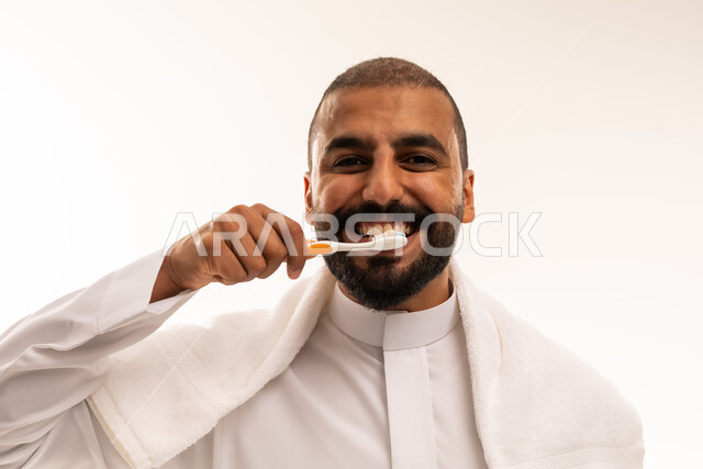 رجل سعودي ينظف أسنانه بالفرشاة بالثوب التقليدي