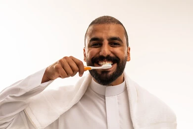 رجل سعودي ينظف أسنانه بالفرشاة بالثوب التقليدي