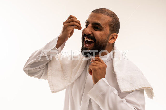 رجل سعودي يستخدم خيط الأسنان بخلفية بيضاء