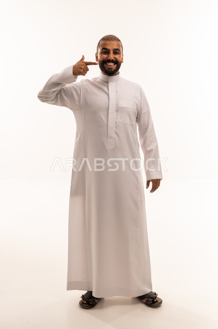 رجل سعودي بالثوب الأبيض يشير إلى ابتسامته