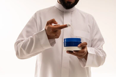 رجل سعودي بالثوب الأبيض يستخدم كريم مرطب