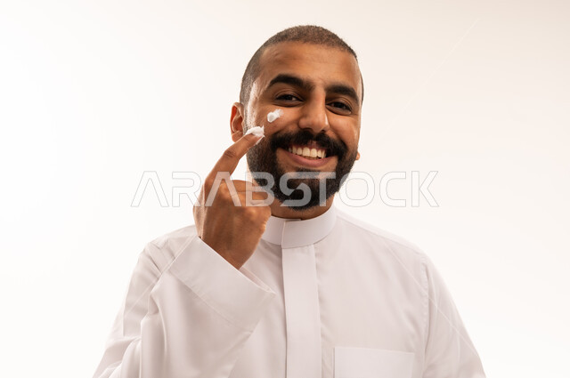 رجل سعودي بالثوب التقليدي يضع كريم البشرة